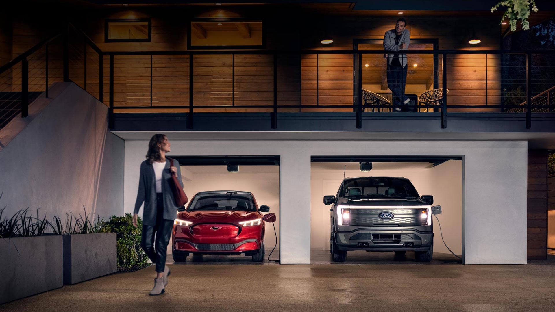 Woman walking out from home garage with a 2024 Mustang® Mach-E and Ford Lightning® truck in plugged-in and charging | McCombs Ford West in San Antonio TX